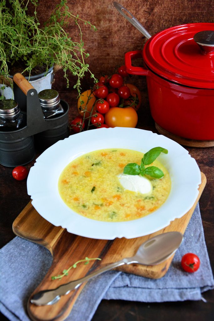 Domaća čorba sa grizom u tanjiru sa kašikom kisele pavlake