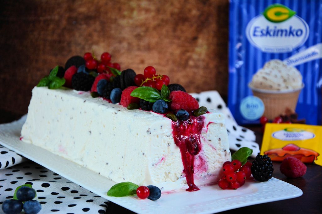 Stracciatella semifreddo sa voćnim prelivom i svežim malinama serviran na letnjem tanjiru
