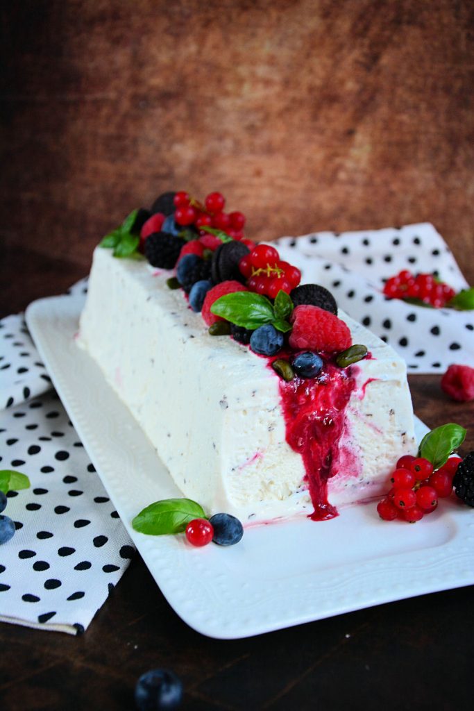 Stracciatella semifreddo sa voćnim prelivom i svežim malinama serviran na letnjem tanjiru